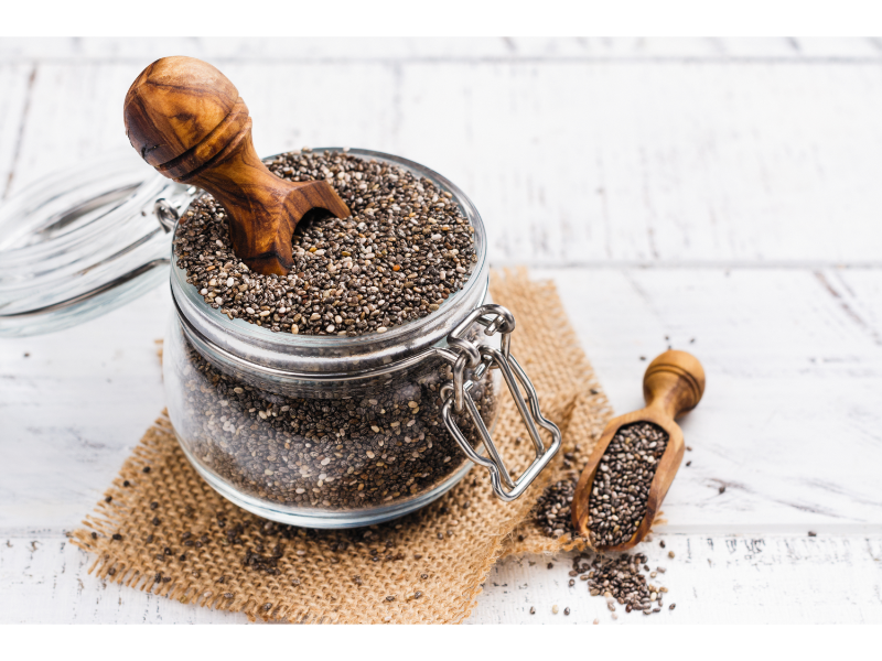 Chia seeds in a glass container with a wooden spoon