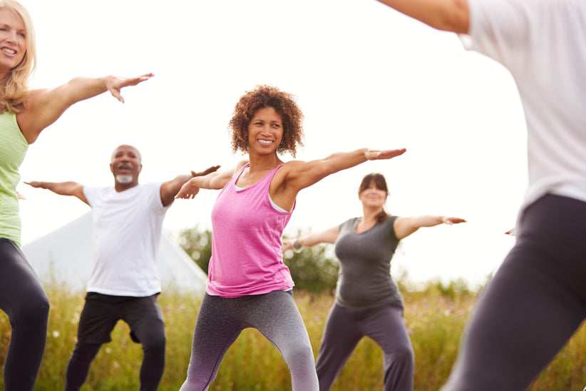 Woman practicing yoga in a field with other people