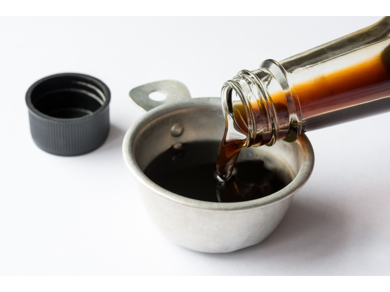 a bottle of coconut aminos pouring into a measuring cup