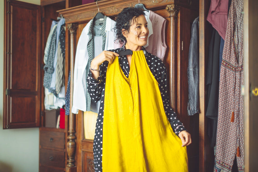 Woman trying on yellow dress while looking in the mirror.
