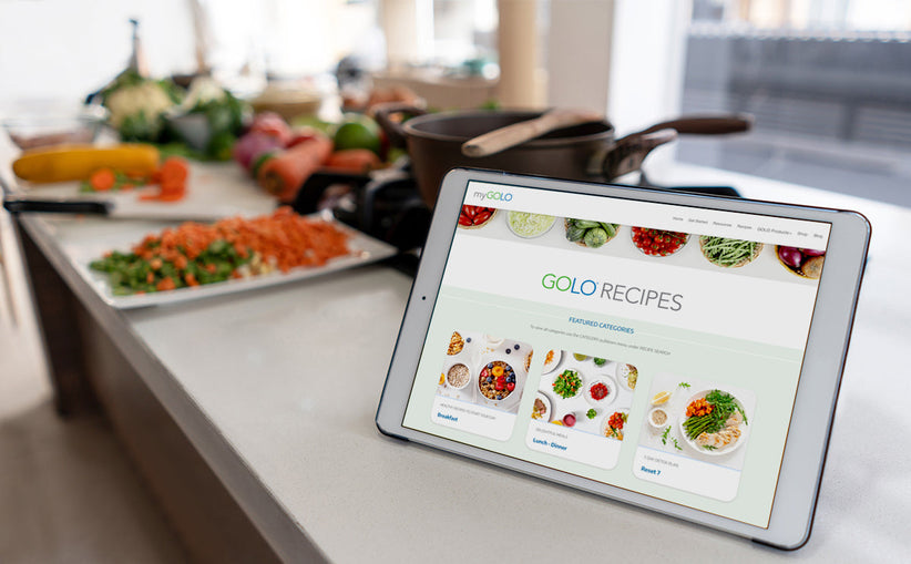 An iPad on the counter with the GOLO Recipes page pulled up. Plates of chopped veggies and other healthy food are in the background.
