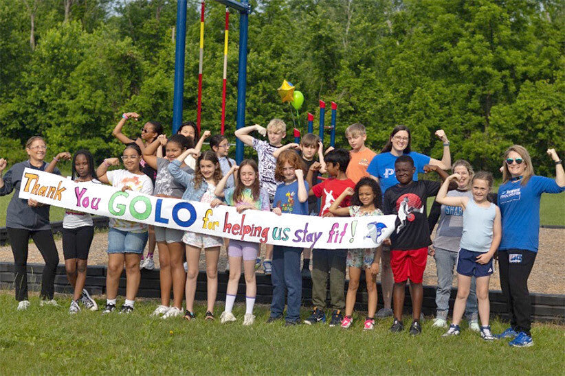 Group of students from John R. Downes Elementary School, plus GOLO President Jennifer Brooks and teachers from the school, holding a banner that says 'Thank you GOLO for helping us stay fit!'