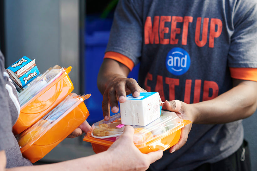 A man donating prepackaged food and small cartons of milk.