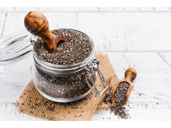 Chia seeds in a glass container with a wooden spoon