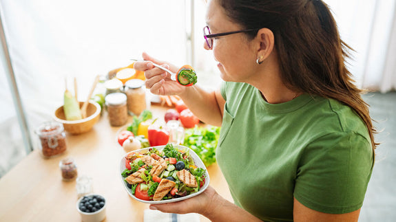 Woman about to take a bit of salad full of healthy greens and chicken
