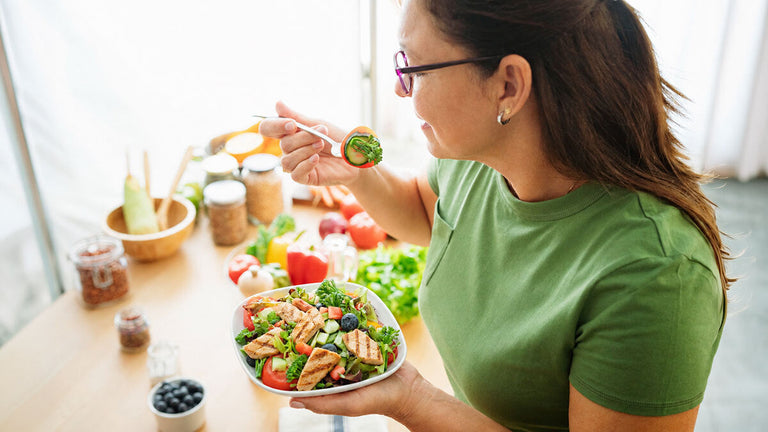 Woman about to take a bit of salad full of healthy greens and chicken