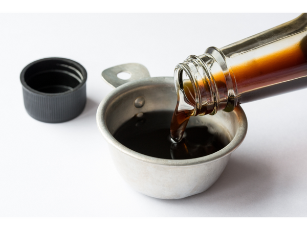 a bottle of coconut aminos pouring into a measuring cup