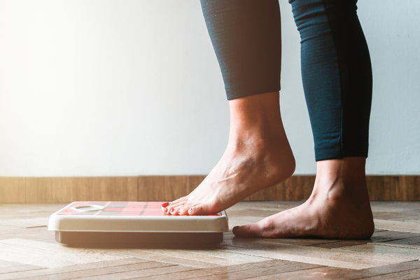 Woman in leggings getting on a scale