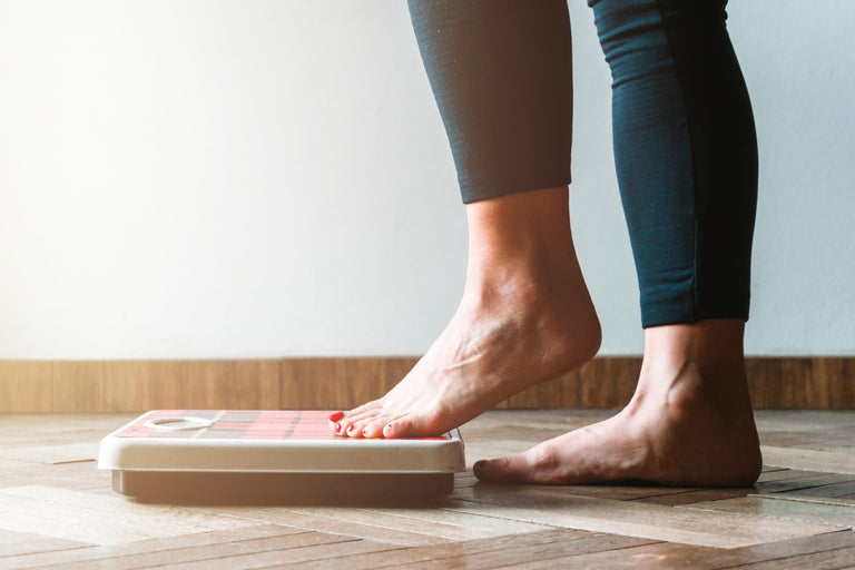 Woman in leggings getting on a scale