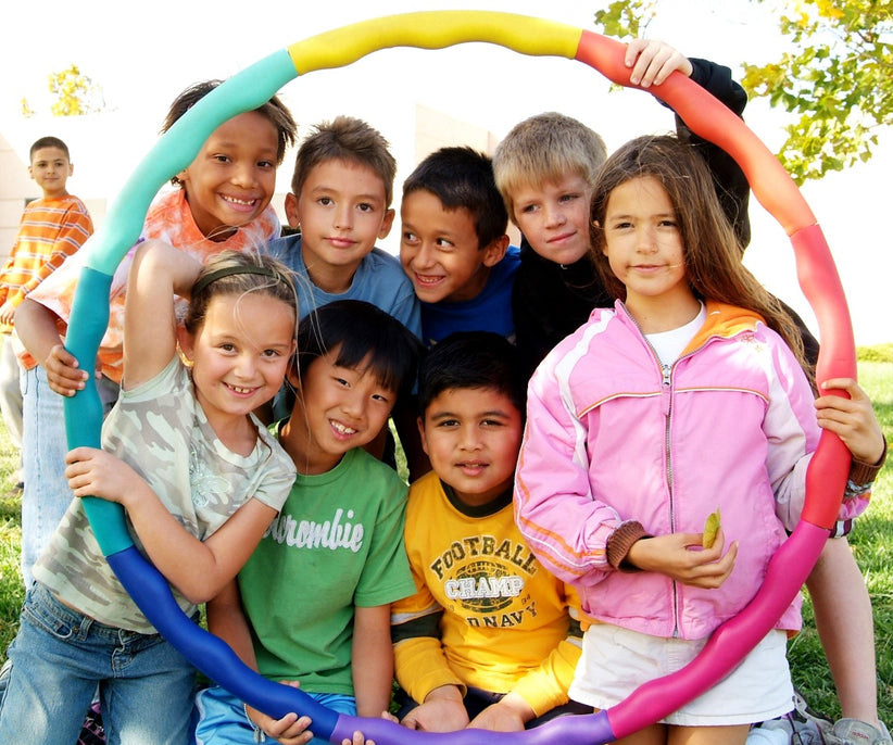 Group of happy, diverse kids holding a colorful hoola hoop.