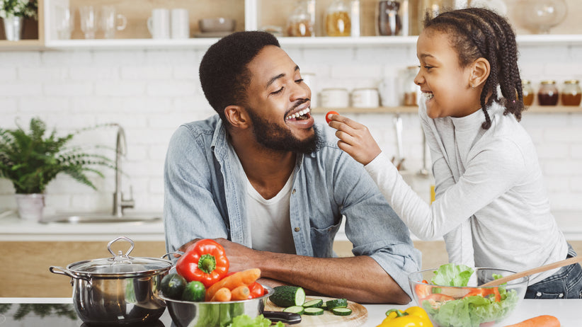 Happy child feeding father tomato