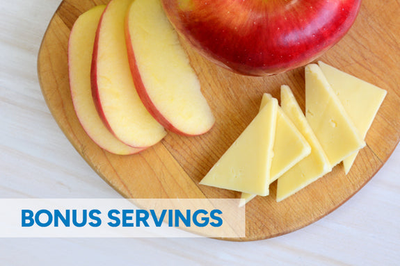 Wooden cutting board featuring sliced apples and sliced cheese. 