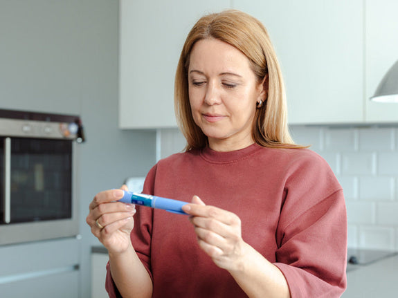 Woman getting a closer look at a GLP-1 medication needle, like she's reading the label.