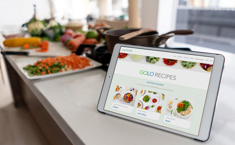 An iPad on the counter with the GOLO Recipes page pulled up. Plates of chopped veggies and other healthy food are in the background. 