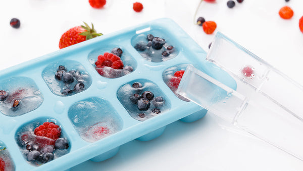 Ice cube tray filled with fruit ice cubes. The ice cubes have blueberries and raspberries in them. 
