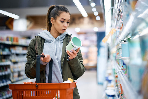 Woman reading the label of yogurt container in the grocery store 