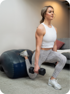 Young woman using dumbbell weights and performing a lunge using the AeroTrainer