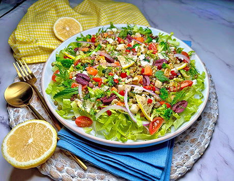 a plate of Mediterranean salad with a lemon on the side