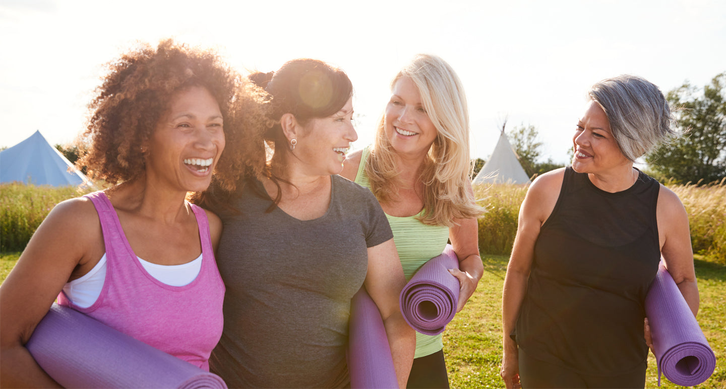 Group of women in workout clothes carrying yoga mats